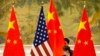 Seorang pegawa sedang memperbaiki posisi bendera AS dan China sebelum sesi pembukaan pembicaraan dagang antara perwakilan AS dan China di Beijing, 14 Februari 2019. (Foto: Mark Schiefelbein/AP Photo)