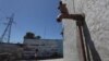 FILE - Residents walk past a leaking communal tap in Khayelitsha township, near Cape Town, South Africa, Dec. 12, 2017.