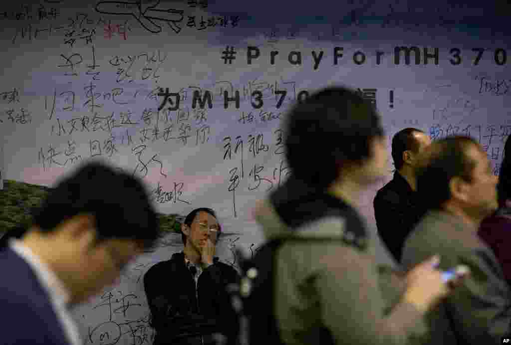 A relative of Chinese passengers aboard Flight MH370 takes a nap against the wall displaying messages of wishes for the passengers during a briefing held by Malaysia officials at a hotel in Beijing, April 11, 2014.