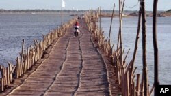 Cambodians ride across a Mekong bamboo bridge in Kom pong Cham, Cambodia Saturday, Dec. 20, 2014. The bridge is constructed every dry season for locals to travel over. The bridge is taken down before the wet session comes to prevent it being washed away. 