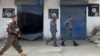 FILE - Afghan police walk past Islamic State militant flags on a wall, after an operation in the Kot district of Jalalabad province east of Kabul, Afghanistan, Aug. 1, 2016. U.S. military officials said Friday that top Islamic State official Abu Sayed was killed July 11 in an airstrike on the group's headquarters in the northeastern Afghan province of Kunar.