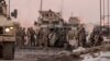 U.S. soldiers search the site where a suicide attacker rammed a car bomb into a NATO convoy, killing two foreign civilian contractors, in the Afghan capital Kabul, Afghanistan, Feb. 10, 2014. 