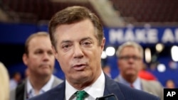 FILE - Then-Trump Campaign Chairman Paul Manafort talks to reporters on the floor of the Republican National Convention at Quicken Loans Arena in Cleveland, July 17, 2016, as Rick Gates listens at back left.