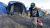 A young migrant pulls a fire extinguisher in a muddy field at a camp of makeshift shelters for migrants and asylum-seekers from Iraq, Kurdistan, Iran and Syria, called the Grande Synthe jungle, near Dunkirk, France, January 25, 2016. 