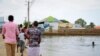 FILE - A child swims in the floodwaters as others walk past, in the town of Beledweyne, in central Somalia, Nov. 4, 2019.