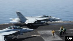 2014年8月8日美国海军水兵在乔治布什航空母舰上指挥执行任务的超级大黄蜂式打击战斗机
