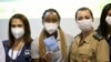 La sprinteuse Rosangela Santos, au centre, montre son certificat de vaccination après avoir reçu une injection du vaccin anti covid Pfizer à Rio de Janeiro, Brésil, le vendredi 14 mai 2021, avant les Jeux Olympiques de Tokyo en juillet. (Photo AP/Silvia Izquierdo)