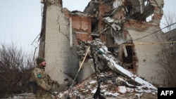 Mwanajeshi wa Jeshi la Ukrainian akipita mbele ya nyumba iliyoharibiwa na waasi wanaoungwa mkono na Russia mjini Mariinka, mkoa wa Donetsk re Februari 7, 2022. (Photo by Aleksey Filippov / AFP)