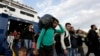 A man carries his belongings as other migrants and refugees arrive on a ferry from the Greek island of Lesbos at the Athens' port of Piraeus, Sept. 30, 2015. 