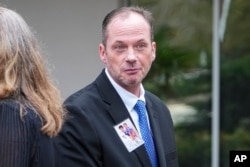 David Smith displays a photo of his two boys as he walks to a press conference after a parole hearing for convicted murderer Susan Smith in Columbia, South Carolina, Nov. 20, 2024.