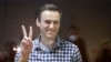 Le chef de l'opposition russe Alexei Navalny fait des gestes pendant son procès au tribunal de district de Babuskinsky à Moscou, en Russie, samedi 20 février 2021.
