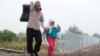 Migrants walk along a railway track as they cross the Hungarian border with Serbia near a collection point in Roszke, Hungary, Sept. 11, 2015.