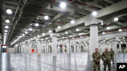 U.S. National Guard members stand at the Jacob Javits Center, Monday, March 23, 2020, in New York. New York City hospitals are just 10 days from running out of "really basic supplies," Mayor Bill de Blasio said late Sunday. De Blasio has called upon…