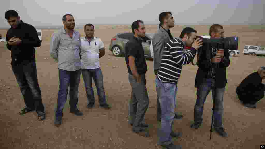 Des Kurdes Turques attendent de regarder à travers l’objectif de la caméra d’un photographe de presse pour voir Kobani, en Syrie, où les Kurdes Syriens et les combattants de l’Etat Islamique se battent, sur une colline dans les périphéries de Suruc à la frontière Turco-Syrienne, diamanche le 12 ocotbre 2014. (AP Photo/Lefteris Pitarakis)