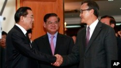Cambodian Prime Minister Hun Sen, left, shakes hands with opposition party leader Sam Rainsy, right, after a meeting, as Sar Kheng, center, deputy prime minister, looks on at the National Assembly in Phnom Penh, Monday, Sept. 16, 2013. 