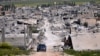 FILE - A car passes in an area that was destroyed during the battle between the U.S.-backed Kurdish forces and the Islamic State fighters, in Kobani, north Syria, April 18, 2015. 