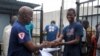 FILE - Cassius Kollie (R), 24, one of four people discharged from an Ebola treatment unit, receives a certificate for being cured of the disease in Paynesville, Liberia, July 20, 2015. 