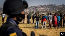 Mwanajeshi mwenye silaha akilinda doria wakati Waziri wa Jeshi la polisi Bheki Cele akizuru Phoenix, eneo jirani lililokumbwa na machafuko na mzozo wa ubaguzi karibu na Durban, Afrika Kusini, Jumamosi, Julai 17, 2021. 