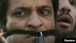 A journalist is seen with a padlock in front of his mouth as others protest against media curbs and emergency rule in Islamabad November 20, 2007. REUTERS/Faisal Mahmood (PAKISTAN)
