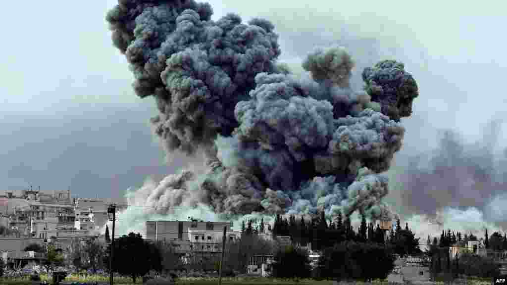Epaisse fumée et débris s'élèvent après une frappe de la coalition menée oar les Etats-Unis à Kobani, en Syrie, dimanche le 12 ocotbre 2014. (AP Photo/Lefteris Pitarakis)