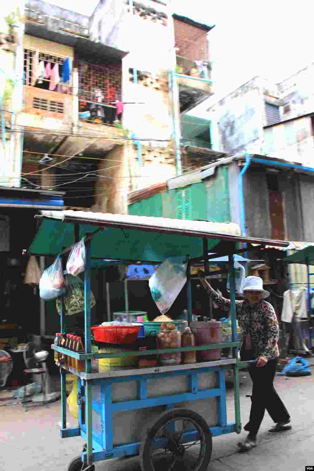 A seller walks past the White Building in Phnom Penh on Friday, September 5, 2014. (Nov Povleakhena/VOA Khmer)