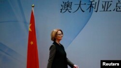 Australia's Prime Minister Julia Gillard walks past a Chinese national flag as she arrives at a welcoming lunch during the Australia China Economic and Trade Forum at a hotel in Beijing, April 9, 2013. The Chinese characters read, "Australia." 