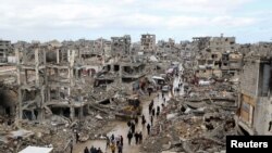 Palestinians walk past the rubble of buildings destroyed during the Israeli offensive, on a rainy day in Gaza City amid a ceasefire between Israel and Hamas, Feb. 6, 2025.