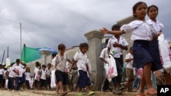 Cambodian schoolchildren walk on a muddy road near the dam site of Steung Mean Chey after they participated in an Intentional Children's Day event in the outskirts of Phnom Penh, file photo. 