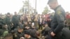 Policías sentados mientras funcionarios de la Defensoría del Pueblo de Colombia hablan con manifestantes que, según las autoridades, exigen que la petrolera Emerald Energy construya carreteras en San Vicente del Caguán, Colombia, el 2 de marzo de 2023.