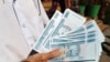 FILE - A man shows new currency notes outside Myanmar Economic Bank Tuesday, Jan. 7, 2020, in Yangon, Myanmar. In an order by Myanmar’s central bank Sunday, April 3, 2022, all foreign currency holdings must be converted into the local currency causing man