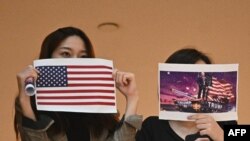 兩名香港女子在一個商場內舉行的抗議中國人大製定港版國安法的集會上手舉美國國旗和川普總統畫像。（法新社2020年5月28日）