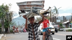 A boy carries metal sheets that were blown away from houses in the winds of Typhoon Goni in Albay province, central Philippines on Nov. 3, 2020.