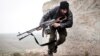 FILE - In this December 17, 2012 file photo, a Free Syrian Army fighter takes cover during fighting with the Syrian Army in Azaz, Syria.