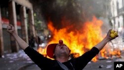 An anti-government demonstrator screams in front of a burning barricade in Santiago, Chile, Oct. 22, 2019. 