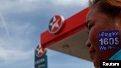 A woman with a sticker on her face reading, "We need $160 per month" protests at a Caltex petrol station in Phnom Penh May 14, 2014. Caltex employees gathered to demand an increase in minimum wage, to $160 per month. 
