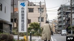 Seorang pria berjalan melewati papan nama Kobayashi Pharmaceutical di luar kantor perusahaan farmasi itu di Tokyo, 28 Maret 2024. (Foto: Yuichi Yamazaki/AFP)
