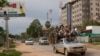 FILE PHOTO - Cambodian passengers sit on top of a pickup truck driven past an unfinished building in Phnom Penh, Cambodia, Monday, Sept. 3, 2007.