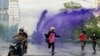 Anti-government protesters escape from a police water cannon with purple dye and tear gas during a protest against the government's handling of the coronavirus disease (COVID-19) pandemic in Din Daeng district of Bangkok, Aug. 29, 2021.