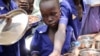 FILE - Children push their plates out to receive a portion of cooked grains during a lunchtime feeding program launched by UNICEF and the World Food Program in in Aweil, Northern Bahr el Ghazal state, South Sudan, March 26, 2019. 
