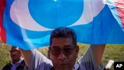 A supporter of People's Justice Party waves its party flag outside the National Palace in Kuala Lumpur, Malaysia, Wednesday, Feb. 26, 2020. Malaysia's ruling alliance collapsed this week after 94-year-old Prime Minister Mahathir Mohamad resigned and…