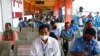 Orang-orang mengenakan masker saat antre untuk divaksinasi COVID-19 dengan vaksin AstraZeneca dalam program vaksinasi massal untuk pekerja transportasi di terminal bus Kampung Rambutan di Jakarta, 11 Juni 2021. (REUTERS/Ajeng Dinar Ulfiana)