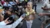 Theary Seng, a Cambodian-American lawyer, dressed in a traditional Khmer Apsara dance costume, speaks to media as she arrives to continue her trial in the municipal court in Phnom Penh, Cambodia, Tuesday, Dec. 7, 2021. (AP Photo/Heng Sinith) 
