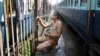 An Indian passenger takes a bath beside rail tracks on a hot summer day at a railway station in Jammu, India, May 25, 2015. 