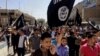 File - Demonstrators chant pro-Islamic State group slogans as they wave the group's flags in front of the provincial government headquarters in Mosul, Iraq, June 2014.