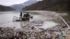 FILE - Utility company workers push the waste to the shore of Lim river near Priboj, Serbia, Jan. 30, 2023.