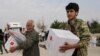 FILE - People hold boxes of aid donated by the Turkish Red Crescent in the border town of Tal Abyad, Syria, Oct. 19, 2019.
