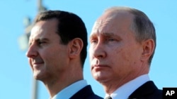 Le président russe Vladimir Poutine, à droite, et le président syrien Bashar Assad regardent les troupes marcher sur la base aérienne de Hemeimeem en Syrie, le 11 décembre 2017.