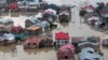 FILE - Flood-affected people row boats past partially submerged buildings in floodwaters in Srinagar, India, Sept. 9, 2014. 
