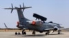 Engineers and support staff sit in the shade of an Embraer EMB-145I aircraft fitted with the India's first indigenous airborne radar system during rehearsals for the Aero India 2015 at Yelahanka air base in Bangalore, India, Feb. 17, 2015.