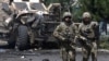 FILE - NATO soldiers walk at the site of a suicide bomb attack in Kabul, Afghanistan, June 30, 2015.